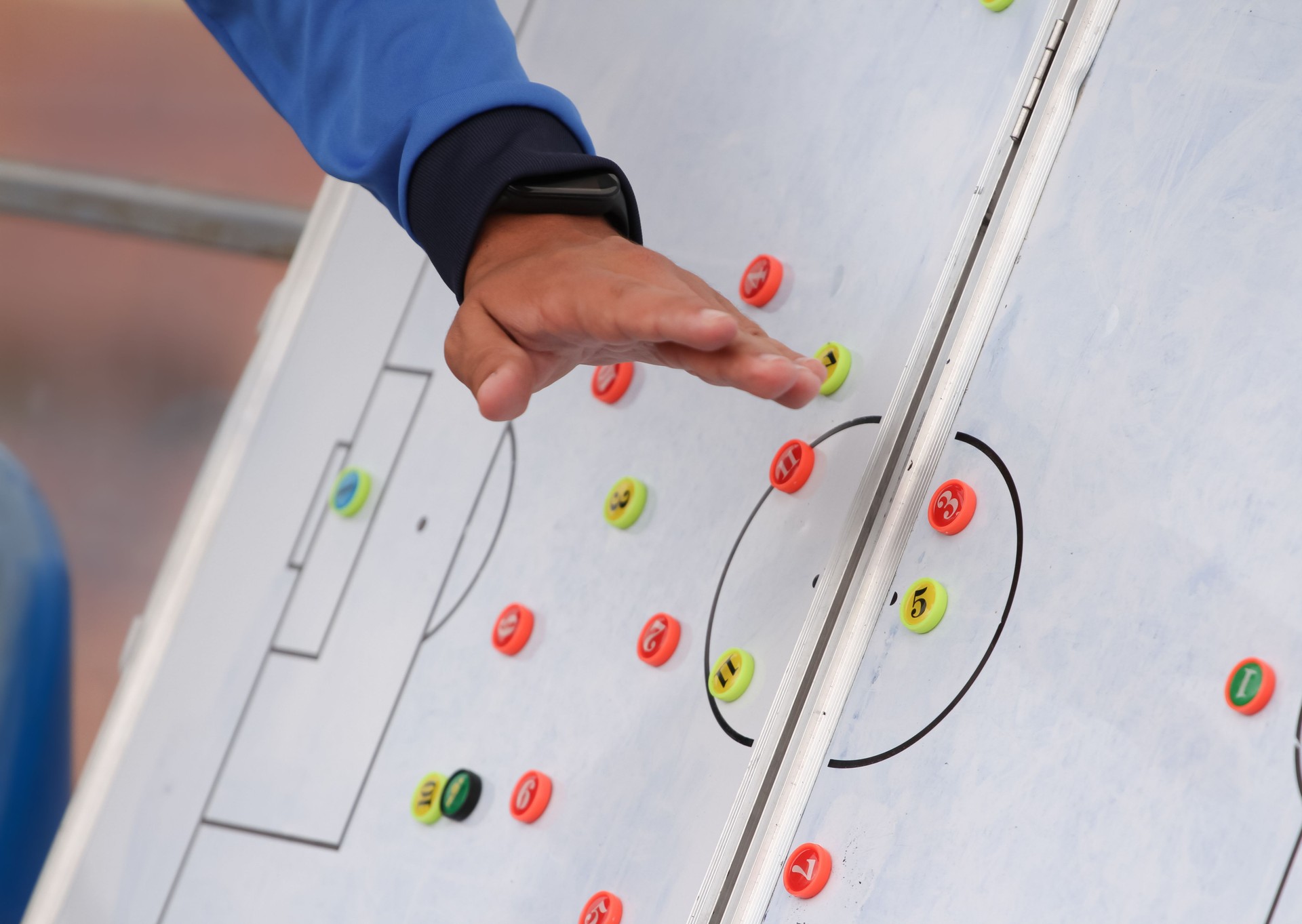 The coach tells the strategy of a football match on a magnetic tablet.