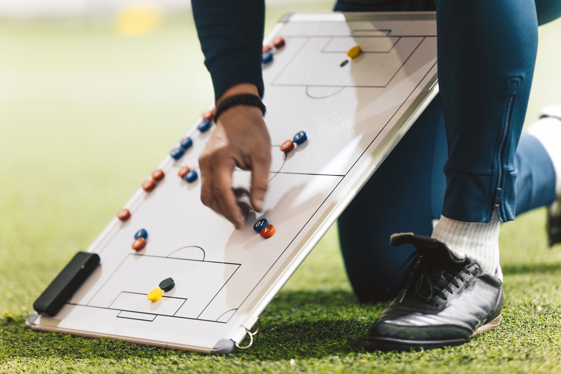 Football Coach Using Soccer Tactics Strategy Board. Coach explaining the game plan to school soccer players